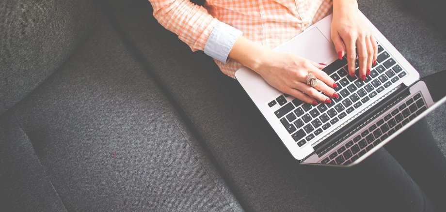 Weibliche Person mit Laptop auf dem Schoß von schräg oben fotografiert