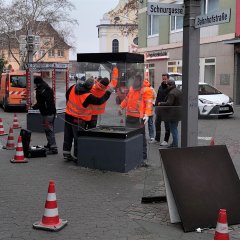 Mehrere Personen montieren Schaukästen ab.