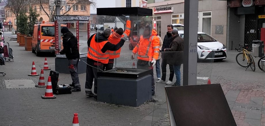 Mehrere Personen montieren Schaukästen ab.